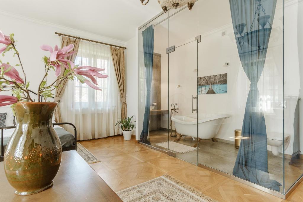 a bathroom with a tub and a vase with flowers in it at Apartamenty w Dworku Cheval in Kraków