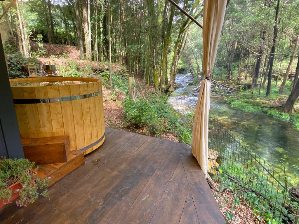 a wooden deck with a hot tub and a river at Wild Glamping Portugal with hot tub to relax in Viana do Castelo in Viana do Castelo