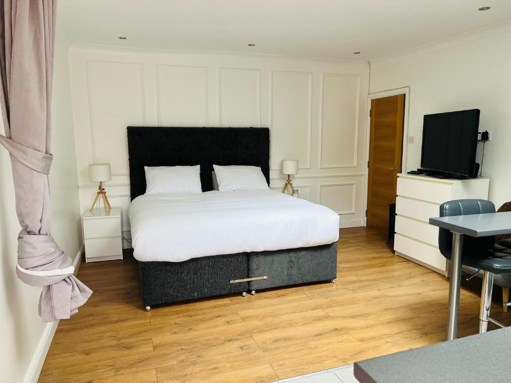 Whiteley’s Cottages studio في دمبارتون: غرفة نوم بسرير وتلفزيون بشاشة مسطحة