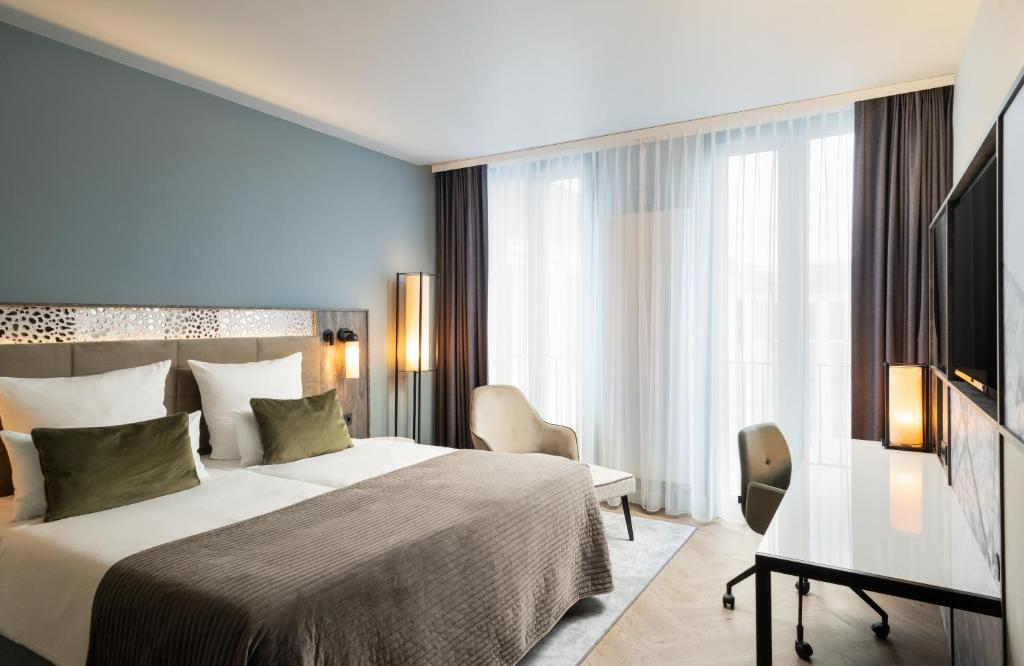 Habitación de hotel con cama y escritorio en Leonardo Royal Hotel Munich en Múnich