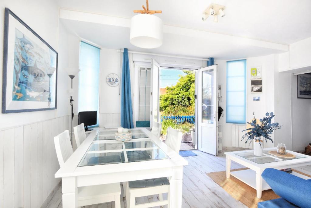 a white dining room with a white table and chairs at La Brise de Barneville - Appt proche plage in Barneville-Carteret
