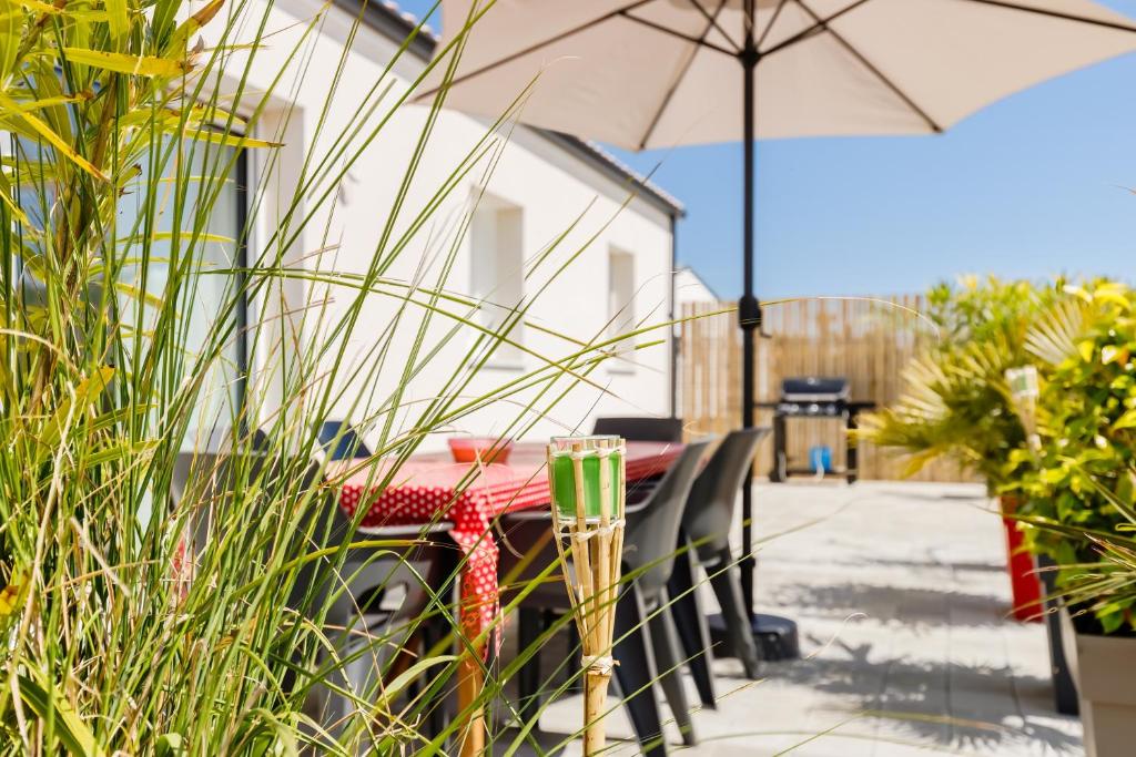 une table et des chaises avec un parasol sur une terrasse dans l'établissement Les Tonnelles - Maison proche plage - Grand jardin, à Saint-Jean-de-Monts