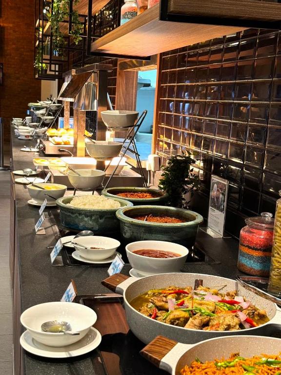 A buffet counter presenting hot dishes, rice, condiments and breakfast accompaniments.