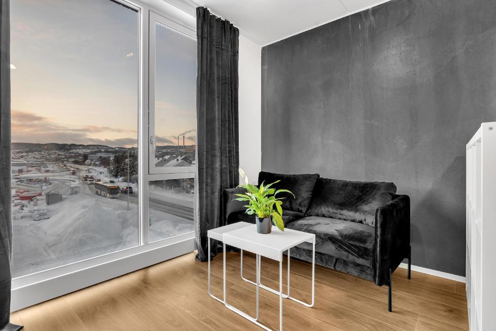 a living room with a black couch and a large window at TotalApartments Stakkevollvegen Studio in Tromsø
