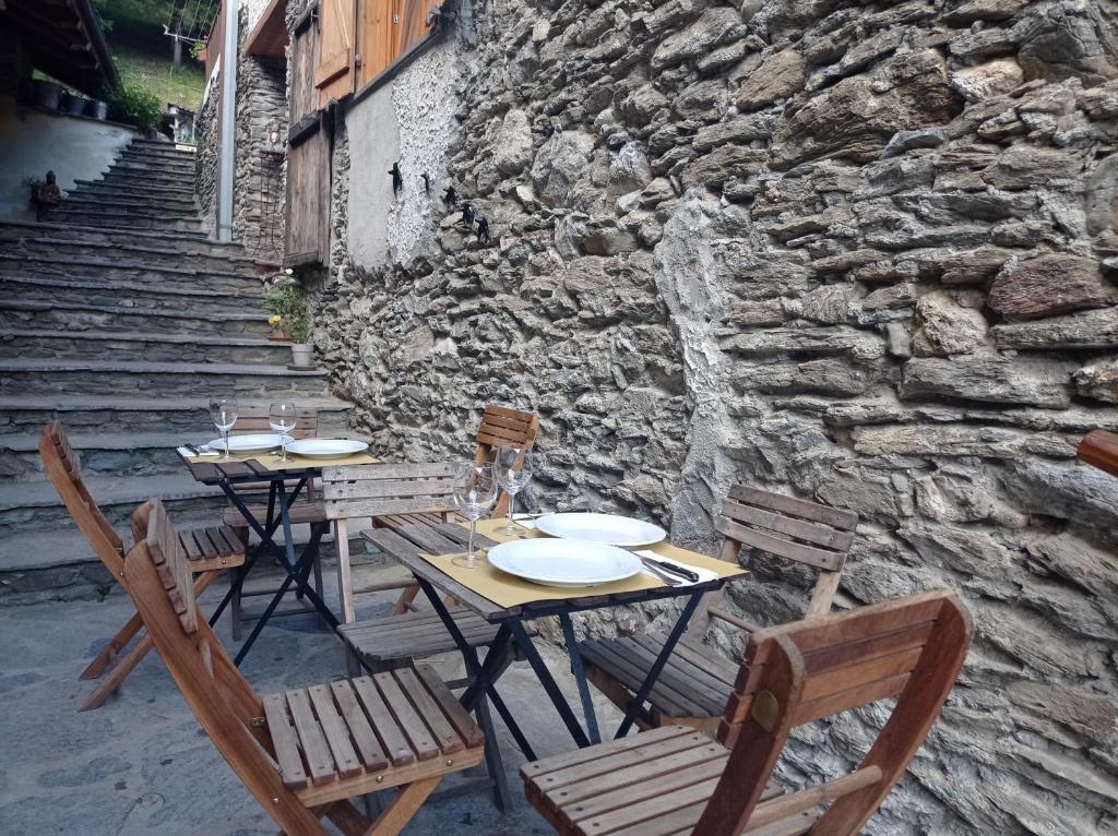 a table and chairs with plates and wine glasses on it at Albergo diffuso La Marmu Osteria della Croce Bianca in Marmora