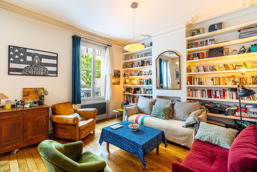 a living room with a couch and chairs and bookshelves at GuestReady - Charming Getaway with Terrace in Paris