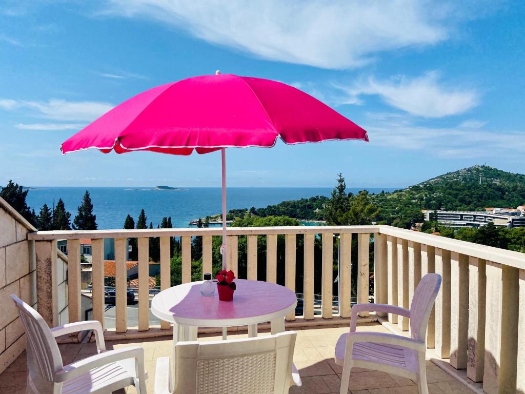 uma mesa com um guarda-chuva rosa numa varanda em Rooms Villa Gala em Mlini