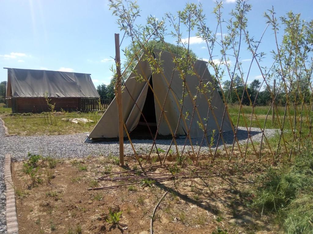 une tente dans un champ à côté d'un bâtiment dans l'établissement Scout-2, à Le Fay