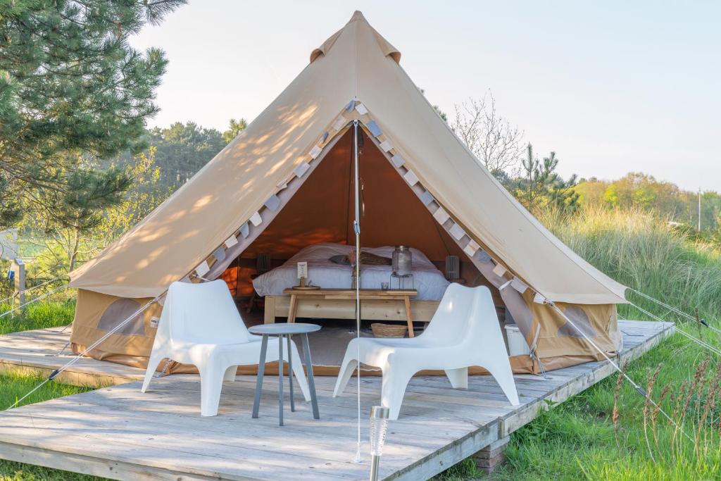 ein Zelt mit zwei Stühlen und einem Bett darin in der Unterkunft Little Canvas Escape in Nes