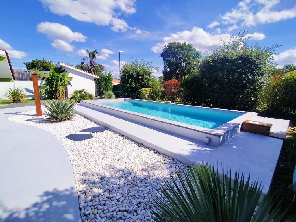 a swimming pool in a garden with a bench at Gîte avec piscine jacuzzi espace bien-être partagés entre Bordeaux et Lacanau océan in Brach
