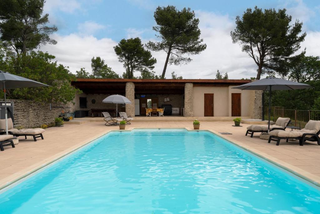 a pool with chairs and umbrellas next to a house at Lou Recati La Ribelle En Provence in Saumane-de-Vaucluse