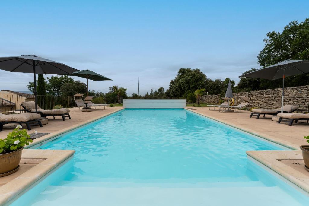 una gran piscina con sillas y sombrillas en Lou Recati La Ribelle En Provence, en LʼIsle-sur-la-Sorgue
