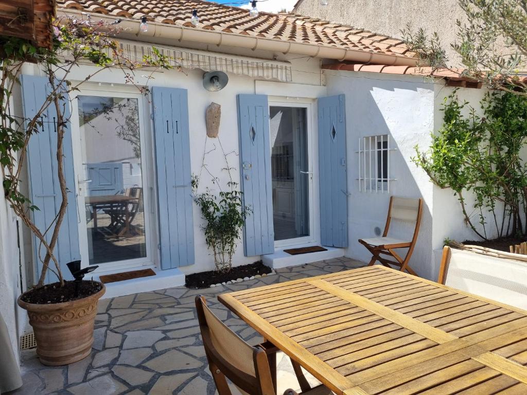 un patio avec une table et des chaises en bois dans l'établissement Jolie petite maison proche mer, à Valras-Plage