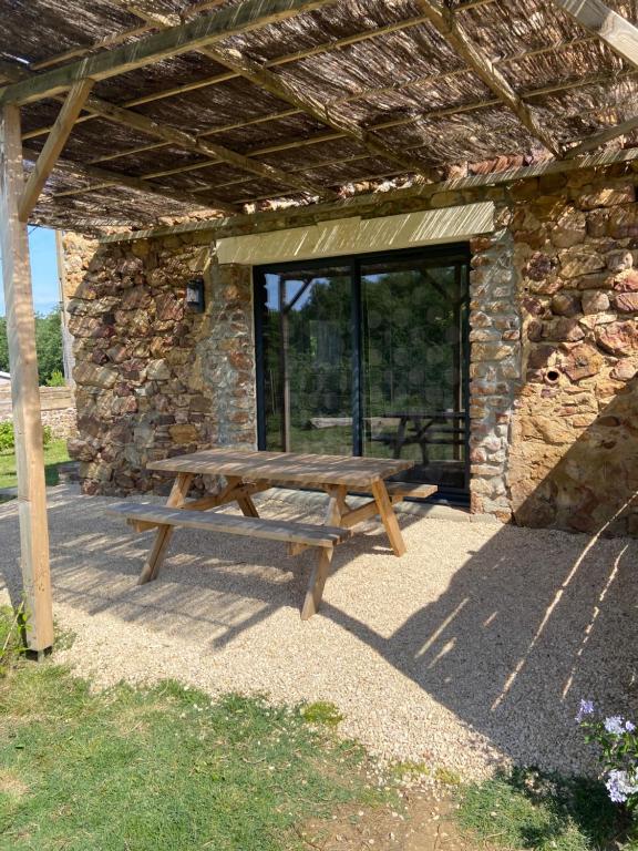 een houten picknicktafel voor een stenen gebouw bij Mas Bô Regard in Aiguèze