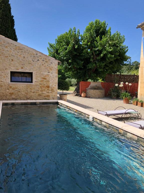 - une piscine en face d'un bâtiment en briques avec des chaises dans l'établissement Mas en Provence, à Mondragon