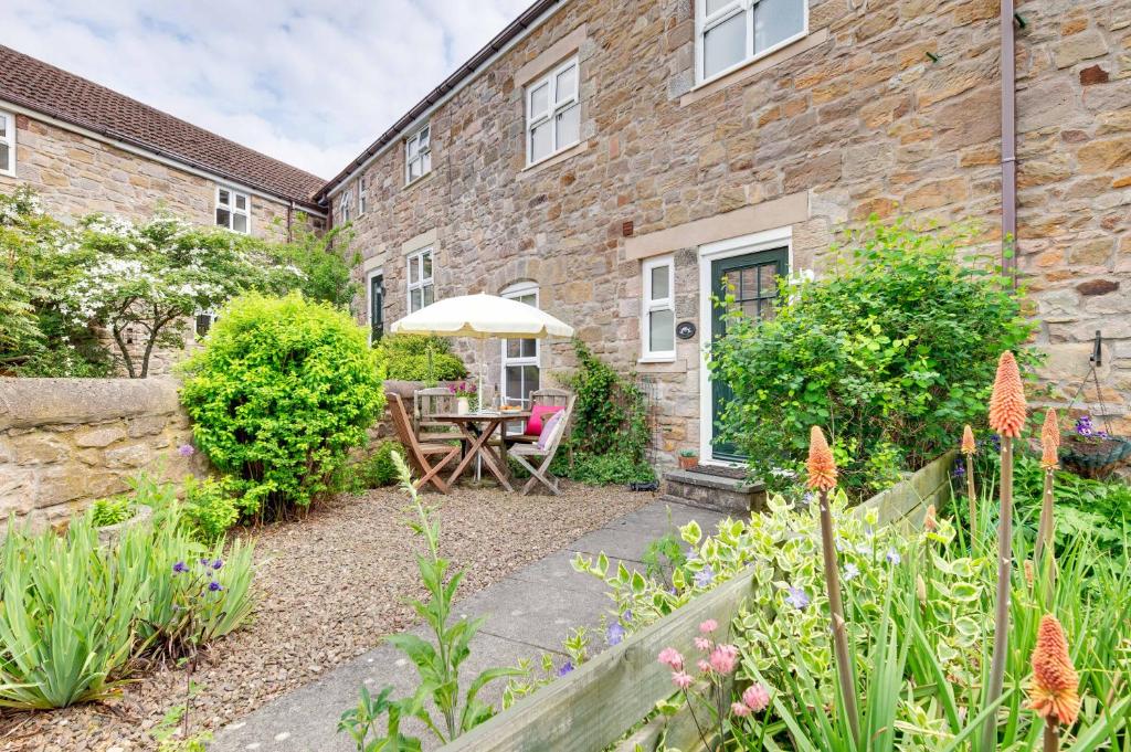 a garden with a wooden table and an umbrella at Honeysuckle Cottage in Doddington