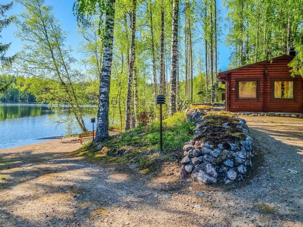 una cabaña de madera en el bosque junto a un lago en Holiday Home Onkilammi by Interhome, en Porras