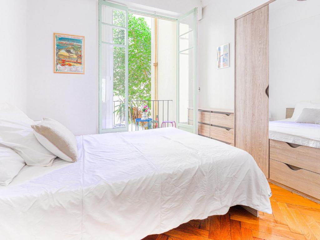 a white bedroom with a large bed and a window at Apartment Le Rossi by Interhome in Nice