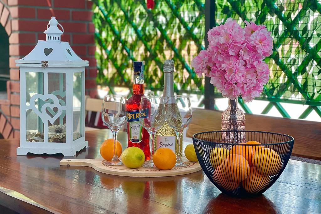 uma mesa com garrafas e um vaso de flores e laranjas em Nola H em Crikvenica