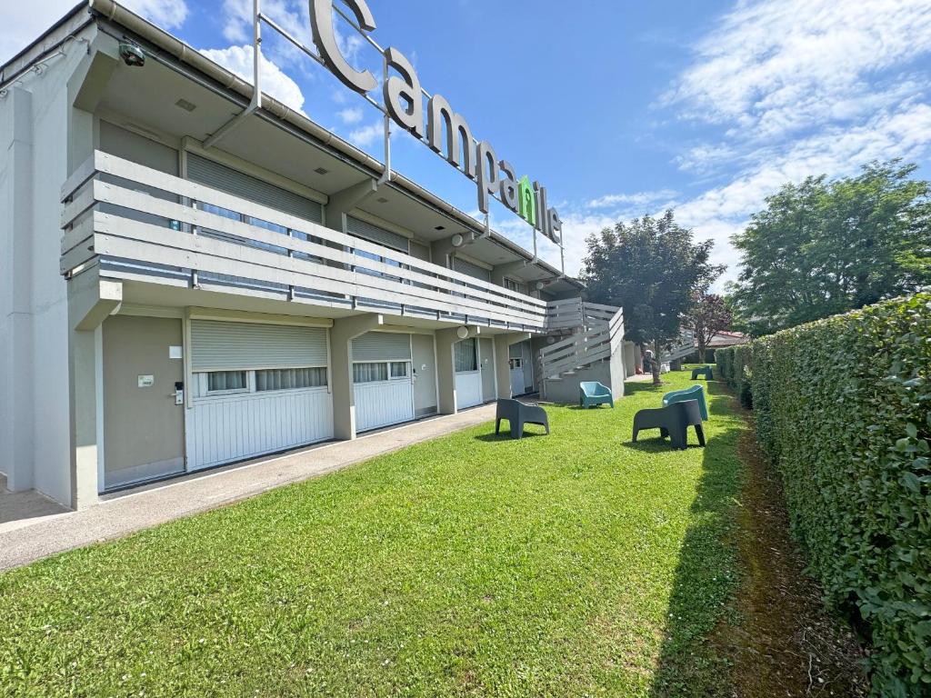 a building with benches in the grass in front of it at Campanile L'Isle d'Abeau - Bourgoin Jallieu in LʼIsle-dʼAbeau