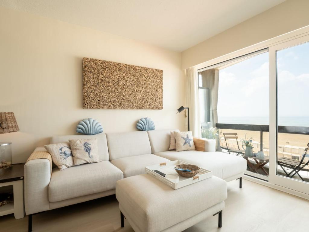un salon avec un canapé blanc et une grande fenêtre dans l'établissement Studio Pacific with parking and sea view by Interhome, à Blankenberge