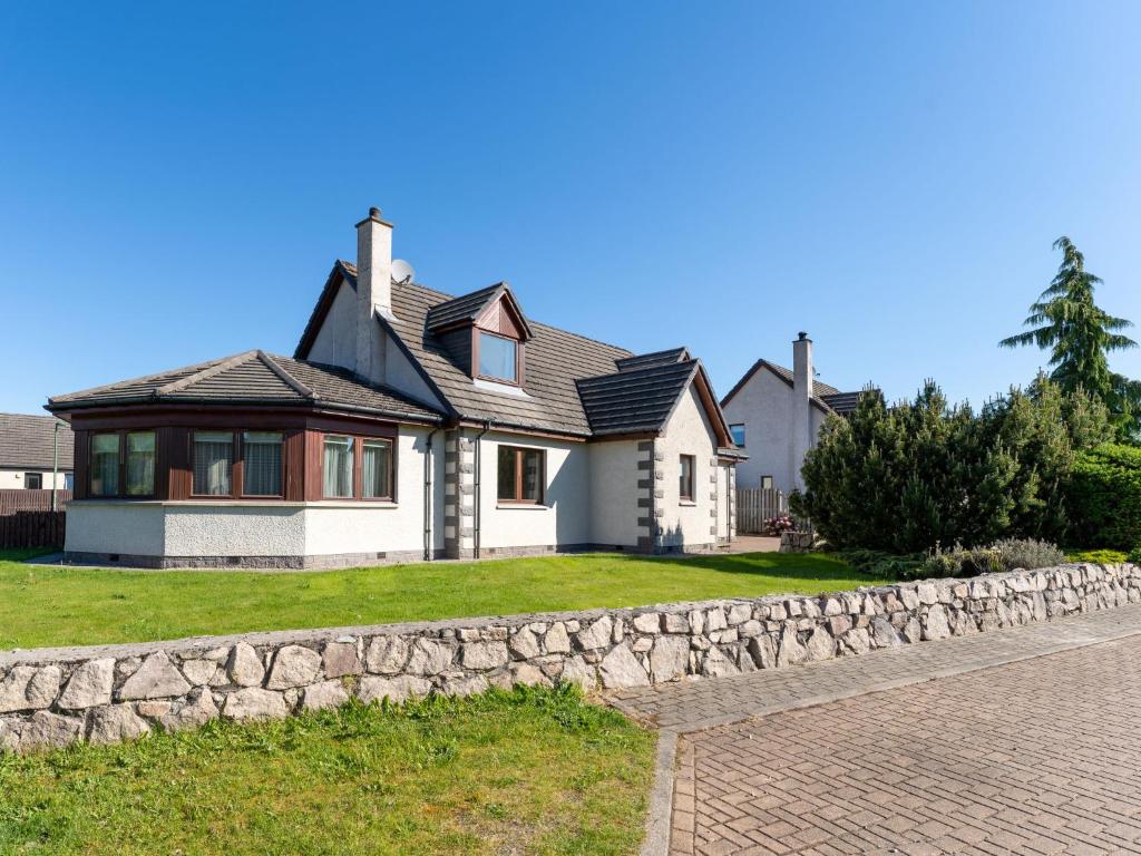 a house with a stone wall in front of it at Villa Craigmore Lodge by Interhome in Aviemore