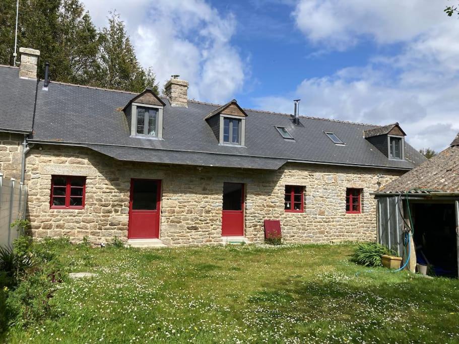une maison en pierre avec des portes rouges et un toit gris dans l'établissement Land & Sea Bretagne, à Trégunc