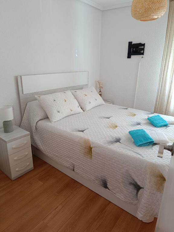 a bedroom with a white bed with blue towels on it at Casa Teo. in Santa Pola