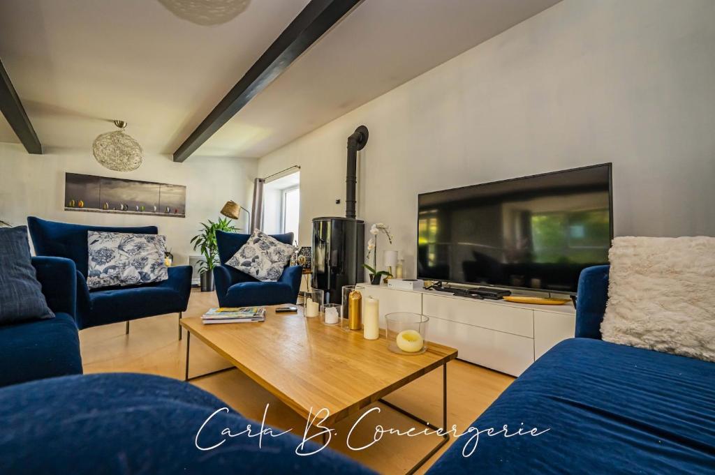 un salon avec une grande télévision et des fauteuils bleus dans l'établissement ROSALIE - MAISON PONT-AVEN 5 PERSONNEs, à Pont-Aven