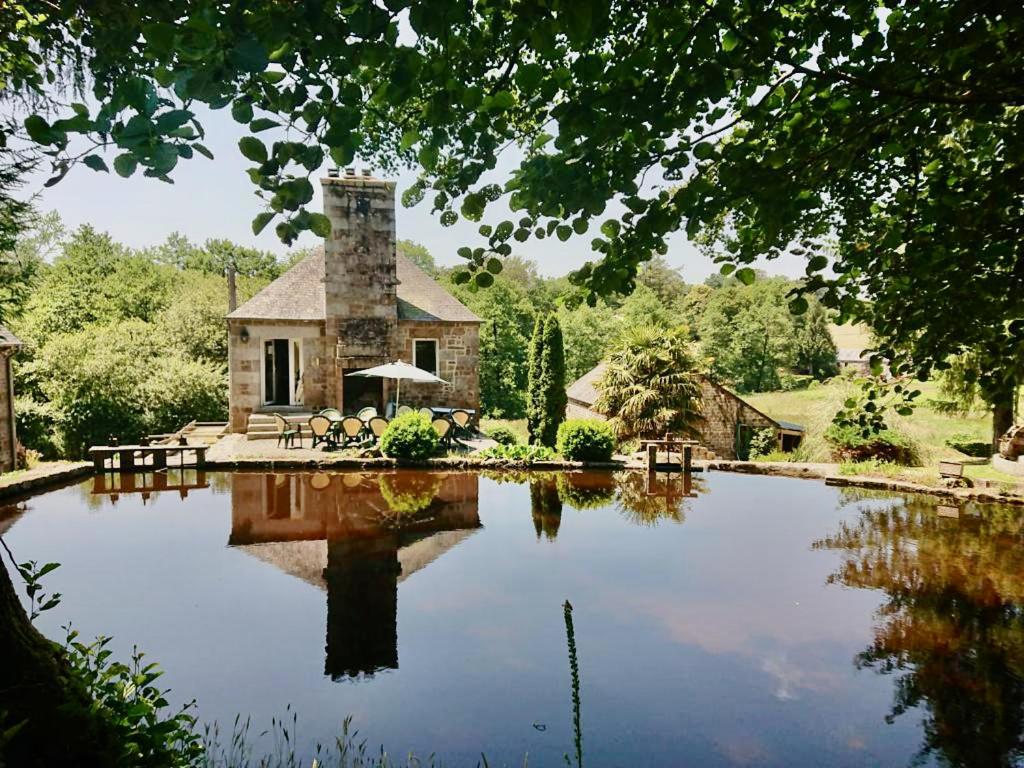 a stone house with a pond in front of it at Moulin du Gast 35pers : jacuzzi sauna billard baby in Le Gast