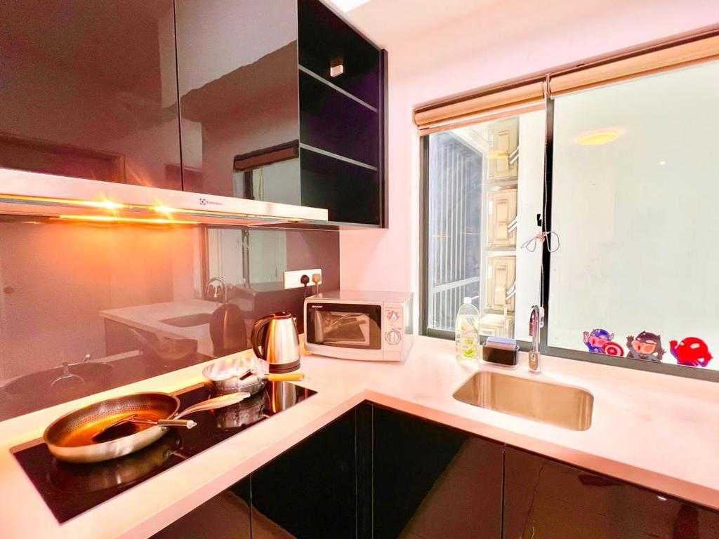 a kitchen with a sink and a microwave at Legoland-Happy Wonder Love Suite-Elysia- Max8pax-with Garden-Pool view in Nusajaya