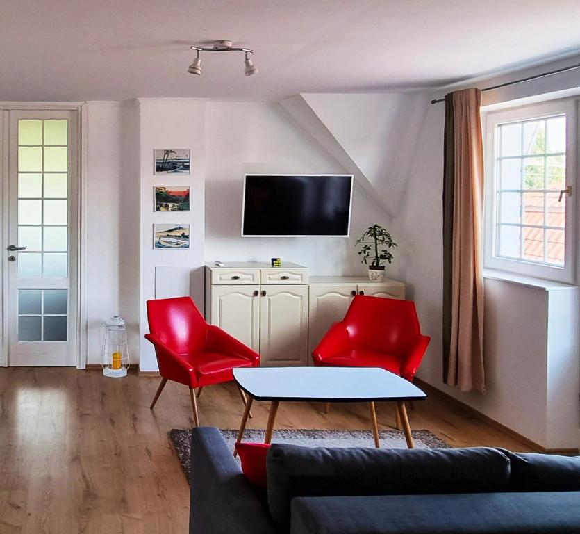 a living room with red chairs and a tv at White Apartment in Keszthely