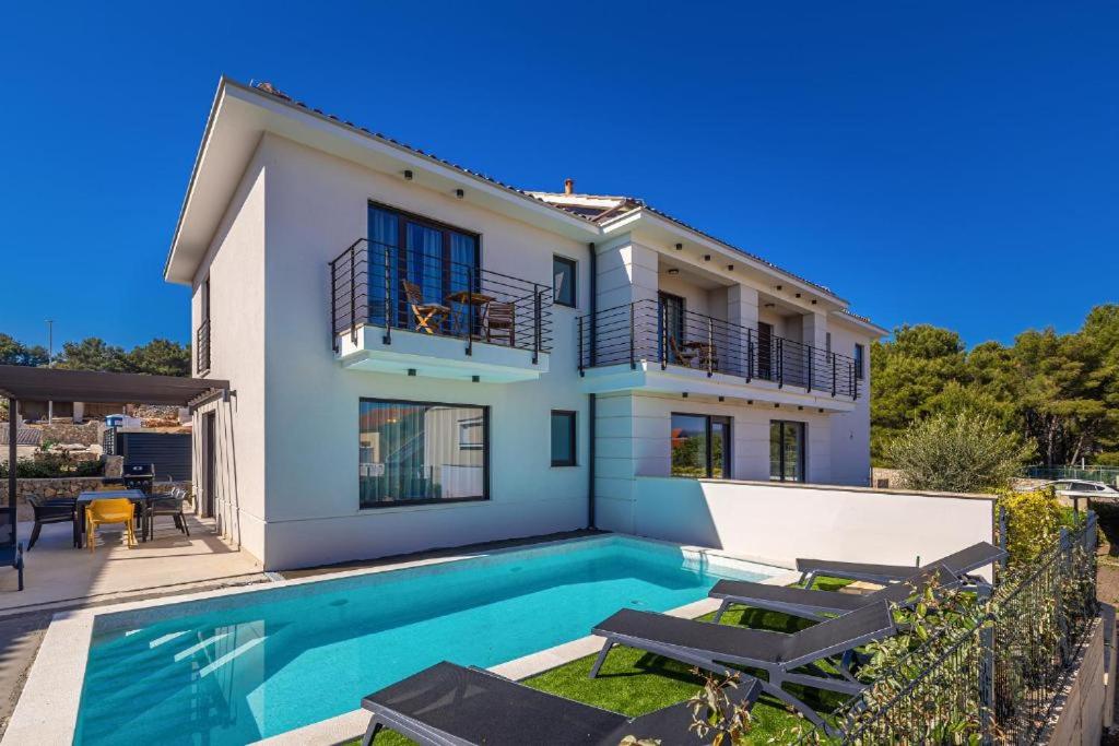 a villa with a swimming pool in front of a house at New villa with pool, sea view, close to a beautiful beach - By TRAVELER tourist agency Krk - ID 2407 in Krk