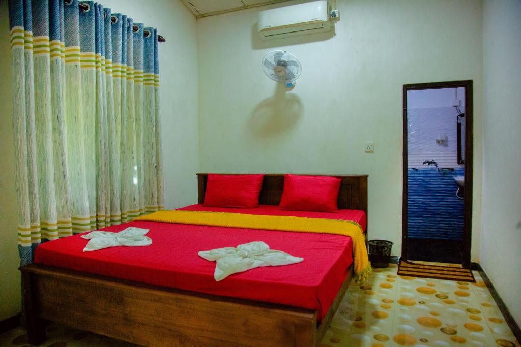 a bedroom with a red bed with towels on it at Sri Shahrukh Lake Resort in Tissamaharama