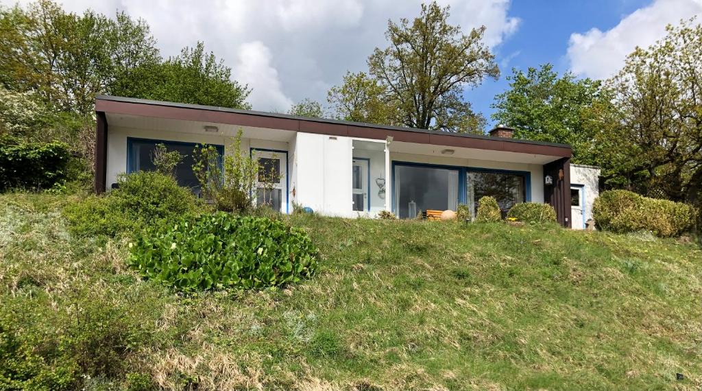 a house on top of a grassy hill at Idyllisch Wohnen im Weserbergland - kompletter Bungalow auf eigenem Grundstück in Polle