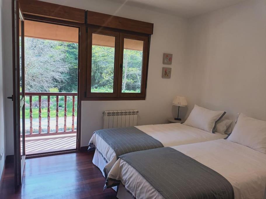 ein Schlafzimmer mit zwei Betten und einem Balkon in der Unterkunft Casa en Treceño in Treceño