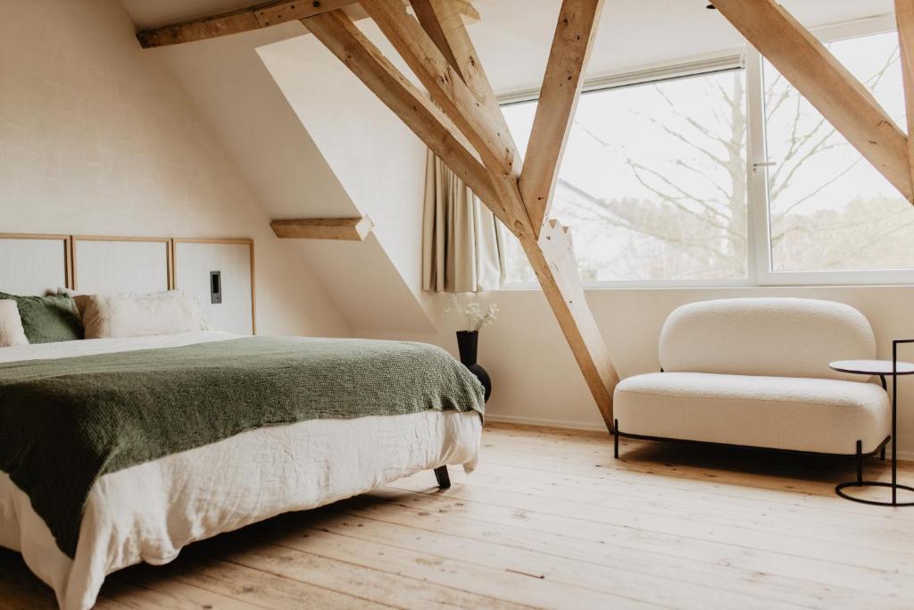 a bedroom with a bed and a chair and a window at Stil 1827 in Sint-Laureins