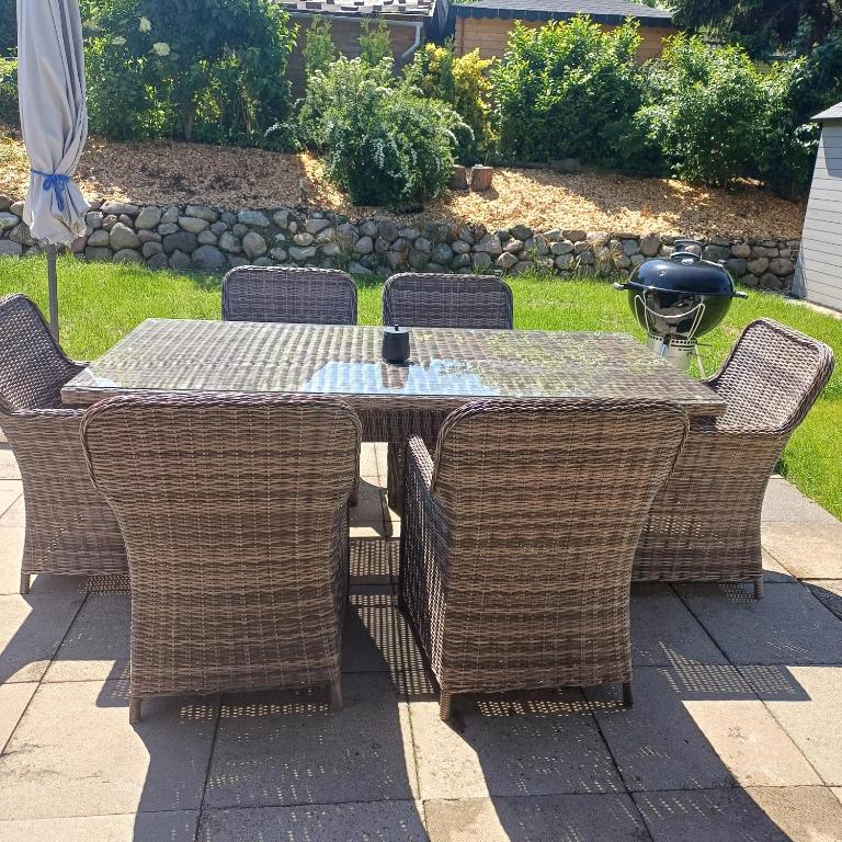 a table with wicker chairs and a table with a drink on it at Ferienhaus mit 4 Schlafzimmer in Pansdorf