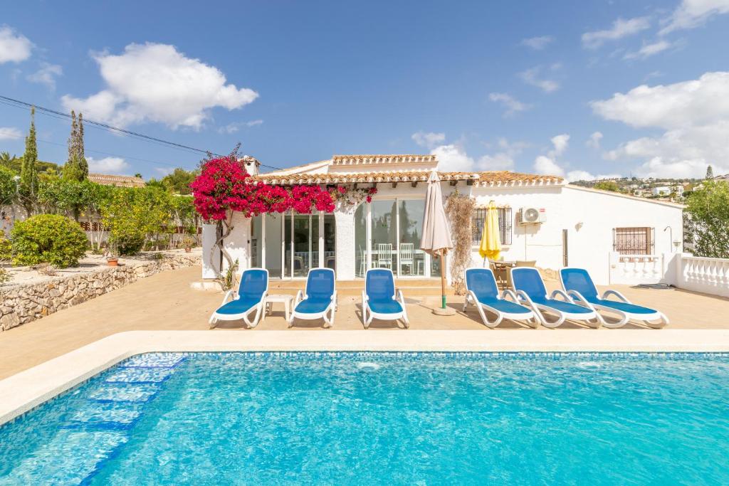 una piscina con sillas azules y una casa en Villa Andes, en Casas de Torrat