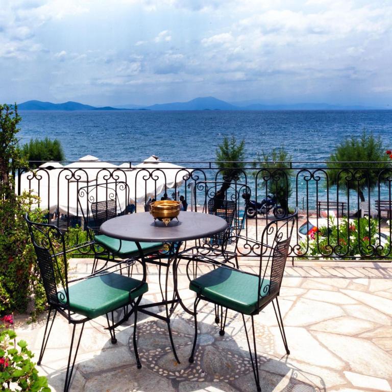 stół i krzesła na patio z widokiem na wodę w obiekcie Afissos Seaside Cottage w mieście Afissos
