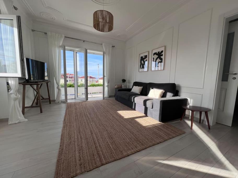 a living room with a couch and a television at Close to Everything Bright Modern Apartment in Nazaré