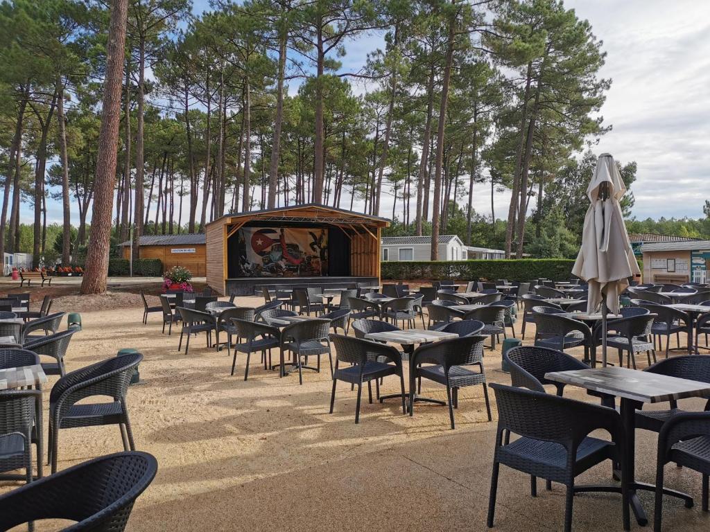un grand groupe de tables et de chaises avec une scène dans l'établissement MH 395 3 chambres et 1 salle de bain dans camping 4 étoiles, à Saint-Julien-en-Born