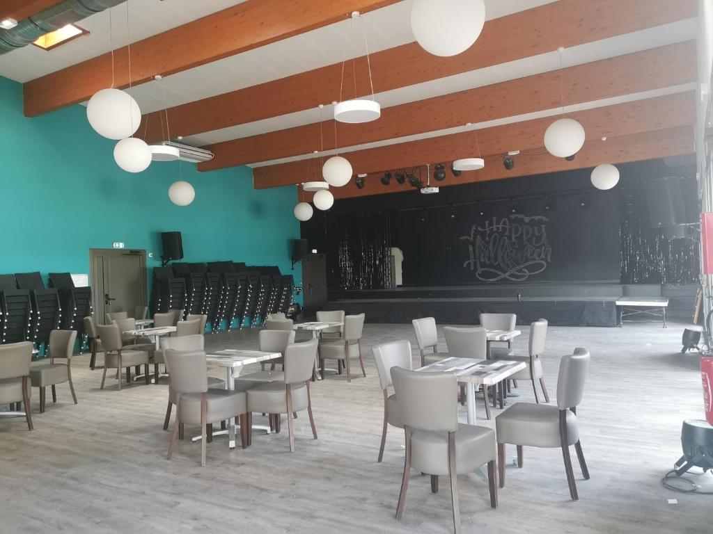 une salle à manger avec des tables, des chaises et une scène dans l'établissement MH 395 3 chambres et 1 salle de bain dans camping 4 étoiles, à Saint-Julien-en-Born