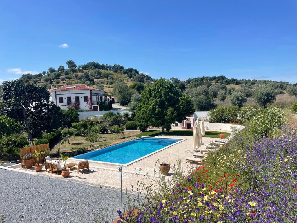 a house with a swimming pool and a garden with flowers at Quinta da Asneira in Montemor-o-Novo