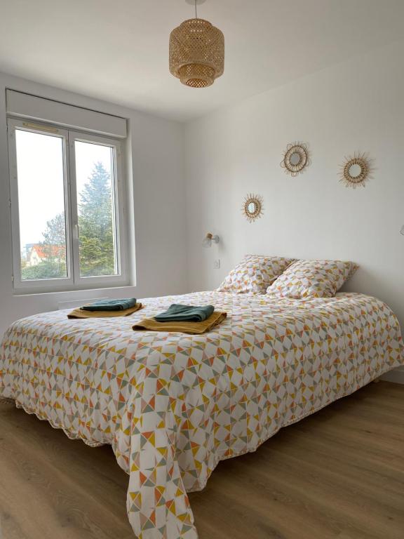 a bedroom with a bed with a comforter and a window at Les Apparts de St Mart in Bréhal