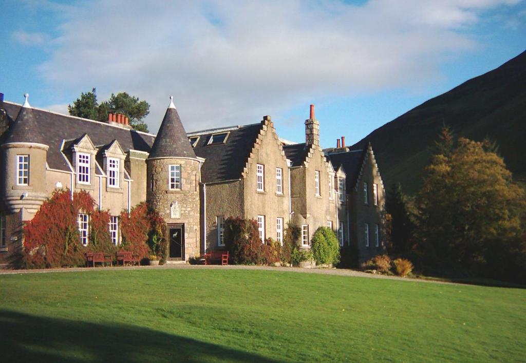 uma casa grande com um grande relvado em frente em Dalmunzie Castle Hotel em Glenshee