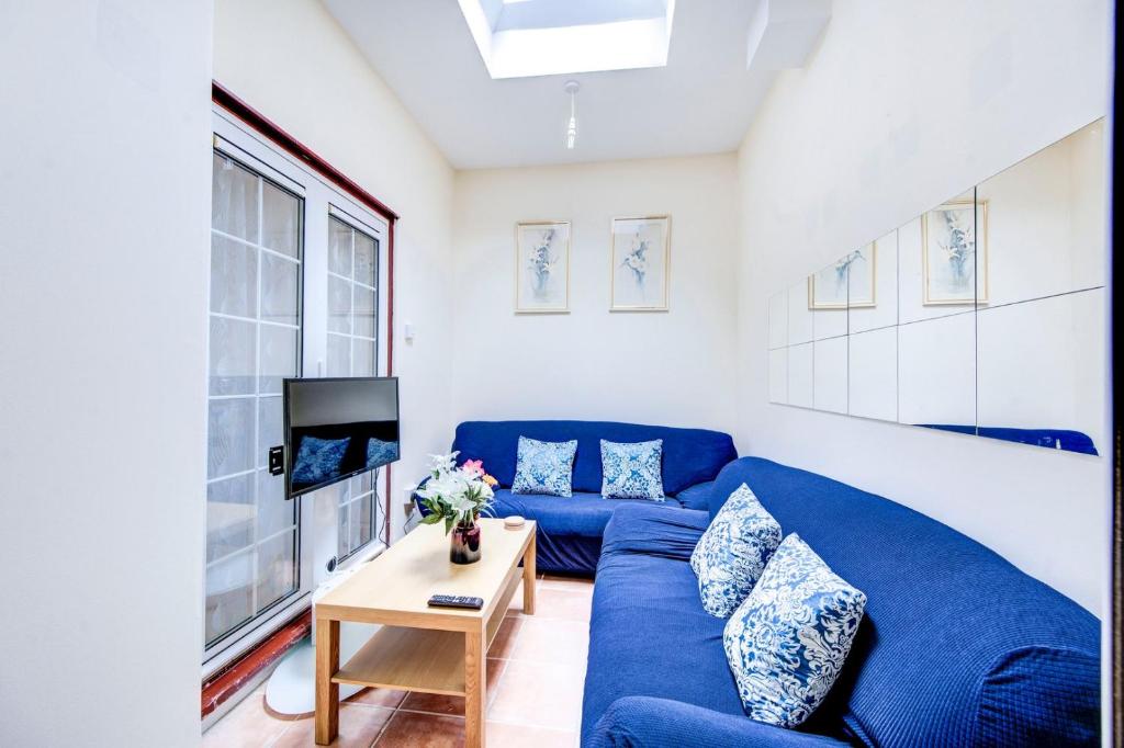 een woonkamer met een blauwe bank en een tv bij GuestReady - Bright Terrace House in Maida Hill in Londen