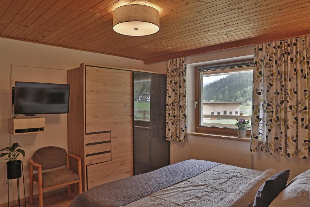 a bedroom with a bed and a tv and a window at Apartment Alpenwelt in Neustift im Stubaital