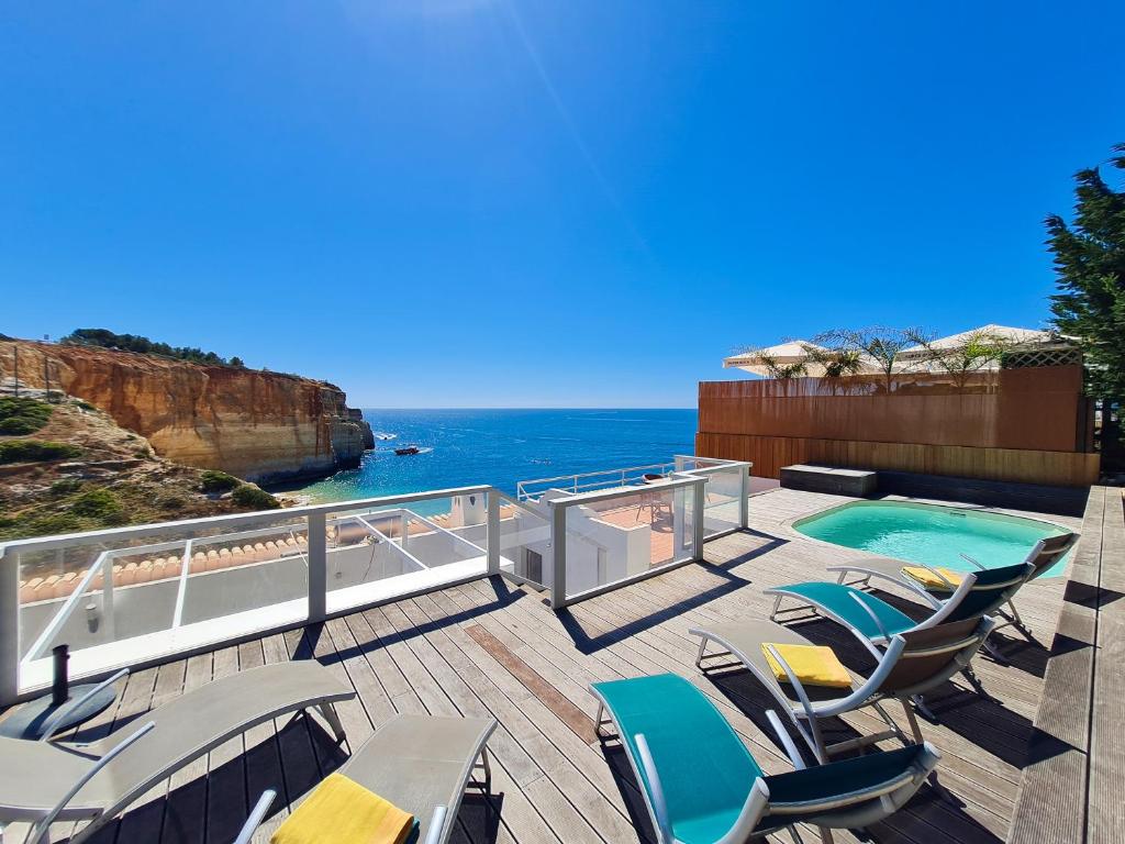 une terrasse avec des chaises, une piscine et l'océan dans l'établissement CASA VERDE - Beach House, Private Terrace & Pool, à Benagil