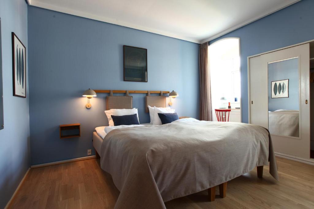 a bedroom with a large bed with blue walls at Hotel Alexandra in Copenhagen